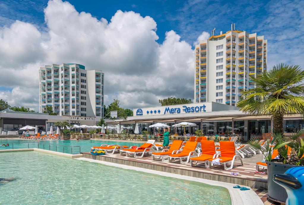 a swimming pool with orange chairs and a hotel at Mera Resort in Venus