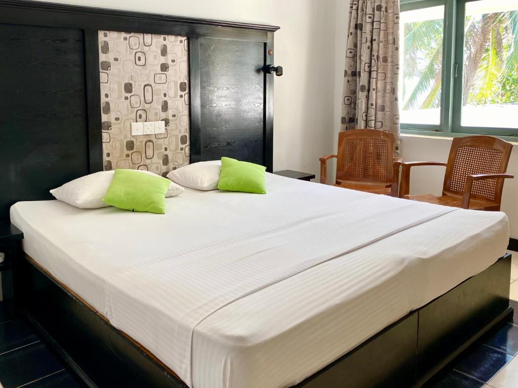 ネゴンボにあるMary Land Beach Hotelの大型ベッド(緑の枕2つ付)
