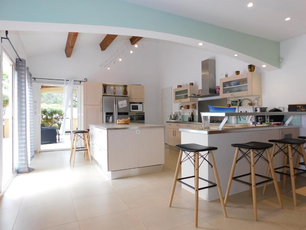 a kitchen with a counter and stools in it at Villa climatisée avec piscine et barbecue in Le Grau-du-Roi