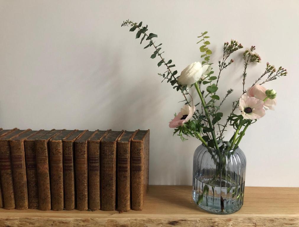 un vase de fleurs assis sur une table avec des livres dans l'établissement DLM Paris, à Paris