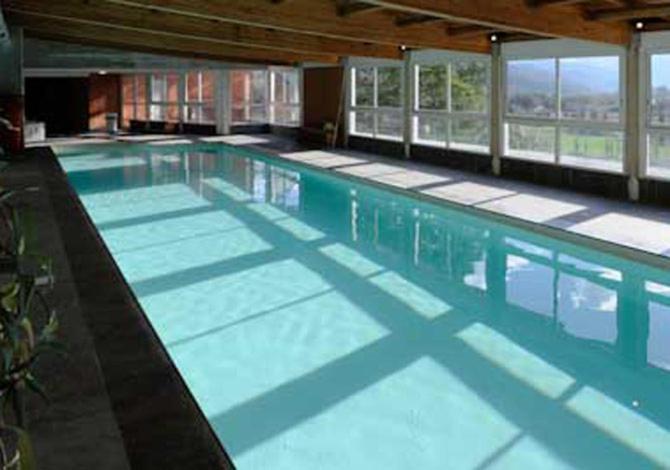 a large swimming pool with blue water in a building at Duplex avec piscine et sauna in Jausiers