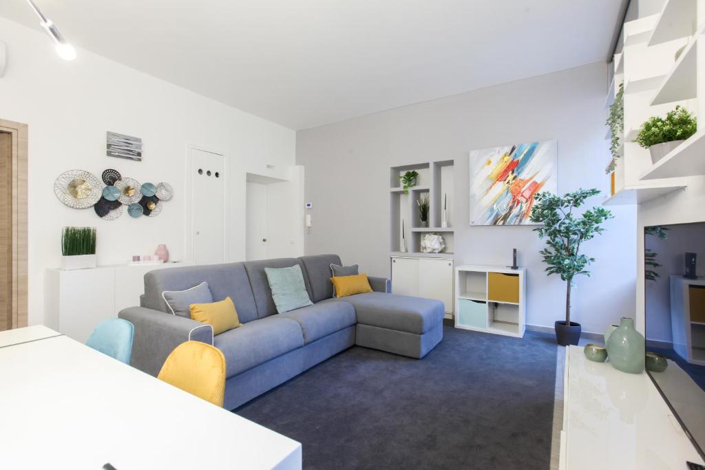 a living room with a blue couch and yellow pillows at Modern apartment close to shopping district in Milan