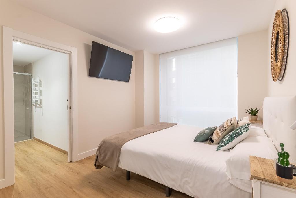 1 dormitorio con 1 cama y TV en la pared en Nuevo y Luminoso en Plaza Moyua en Bilbao