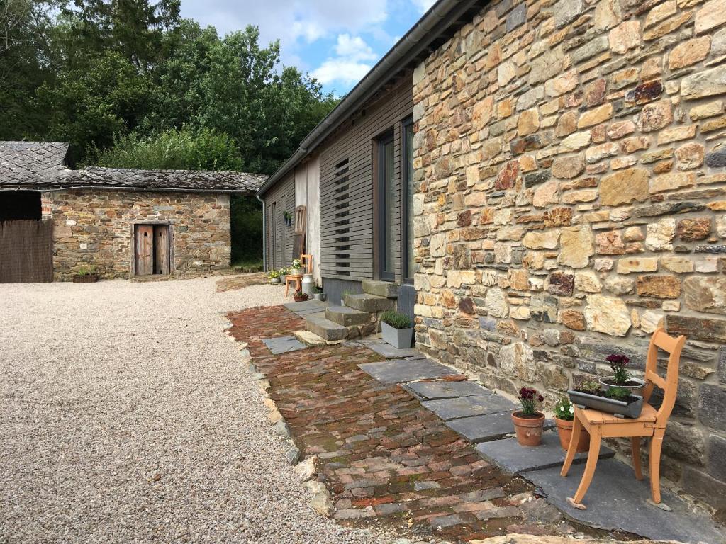 un bâtiment en pierre avec une chaise et un mur en pierre dans l'établissement La Maison de Julienne - Ligneuville, à Malmedy