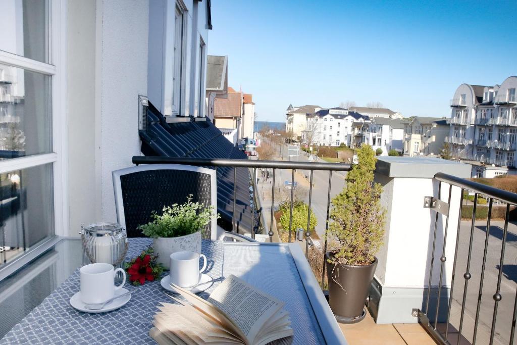 Un balcón con una mesa con un libro y tazas de café en Ferienwohnung Katharina - Urlaub mit Strandkorb en Kühlungsborn