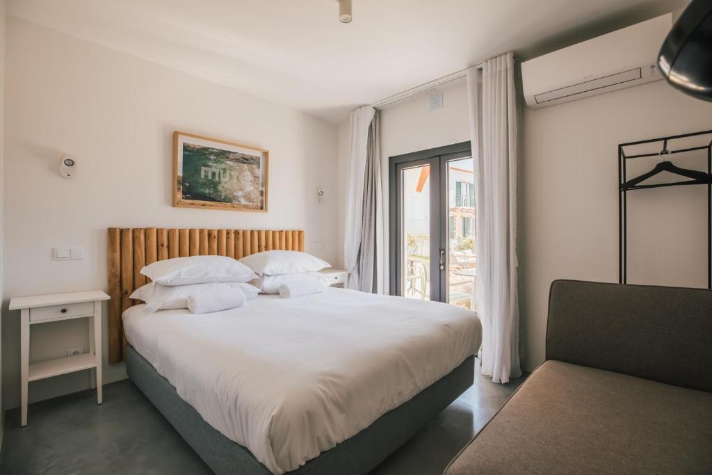 a bedroom with a large white bed and a window at MUTE Hostel Porto Covo in Porto Covo
