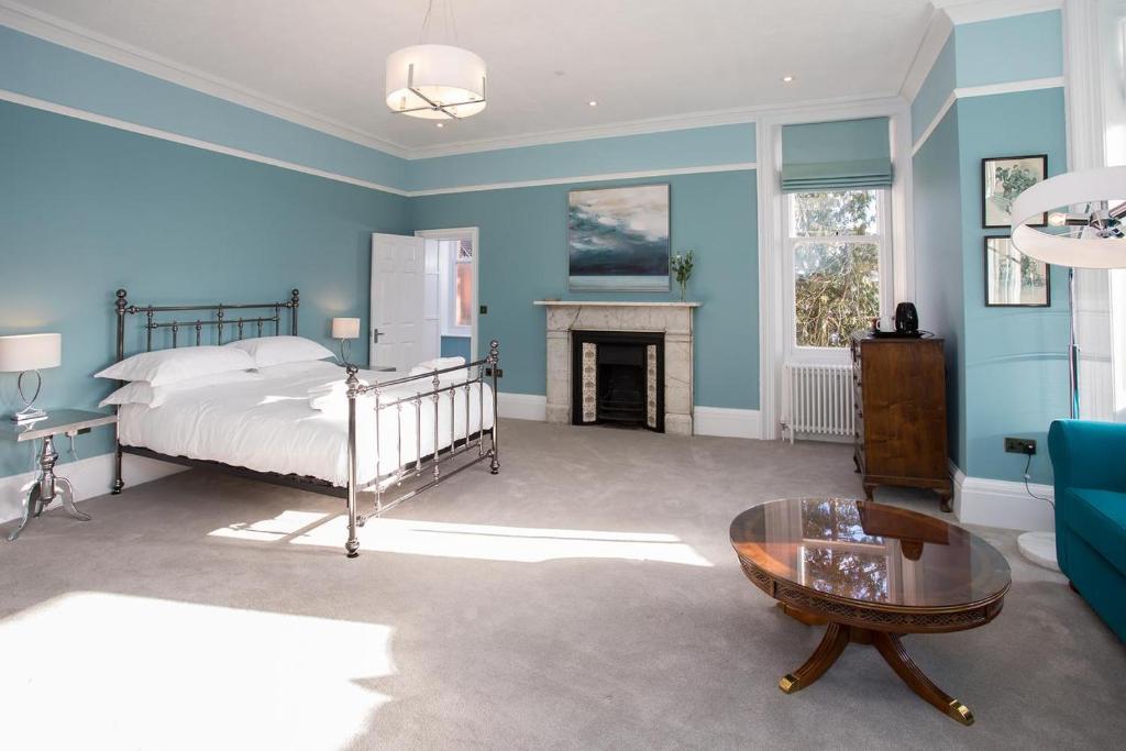 niebieska sypialnia z łóżkiem i kominkiem w obiekcie Torrington Hall w Saint Albans