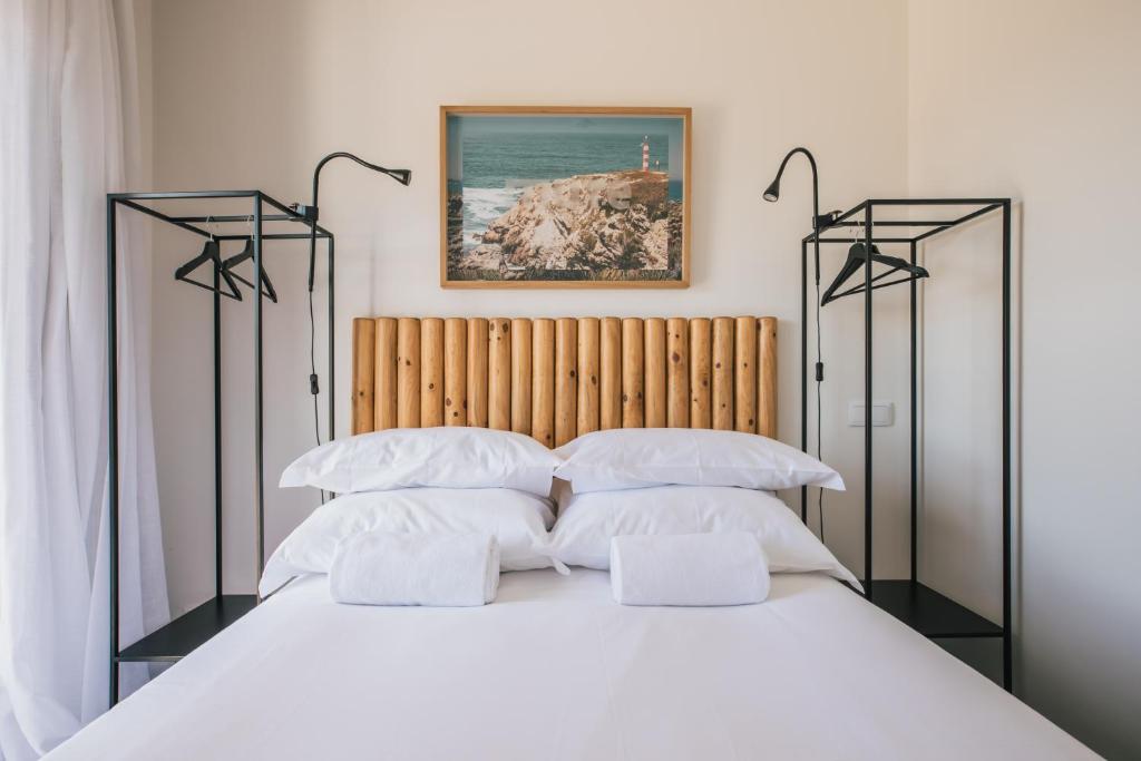 a bedroom with a large bed with white pillows at MUTE Hostel Porto Covo in Porto Covo
