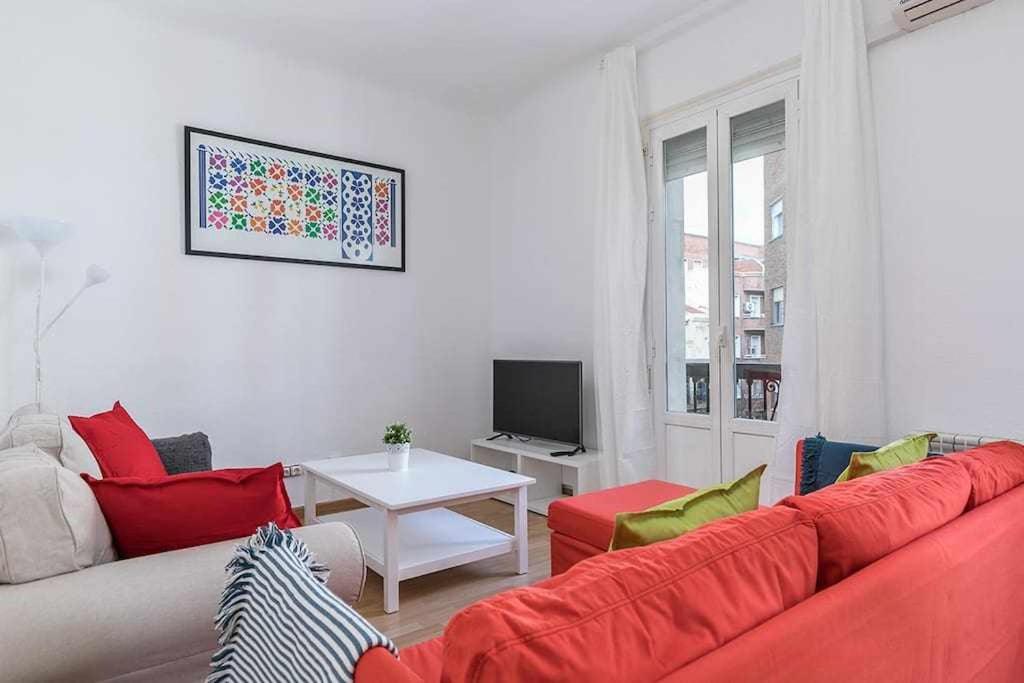 ein Wohnzimmer mit einem roten Sofa und einem TV in der Unterkunft Agradable piso de dos habitaciones en Chamberí in Madrid