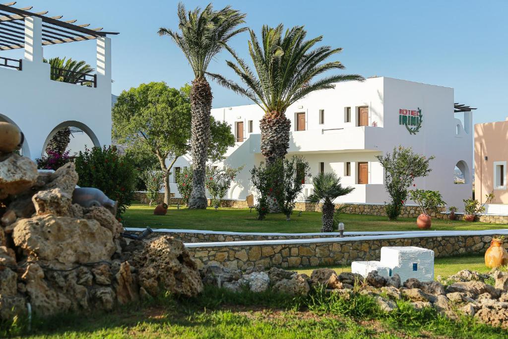 a house with palm trees and a stone wall at Irini Hotel in Afiartis