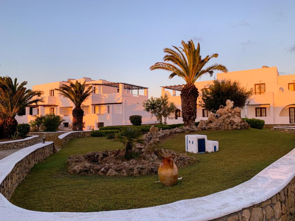 a garden with palm trees and a vase on the grass at Irini Hotel in Afiartis