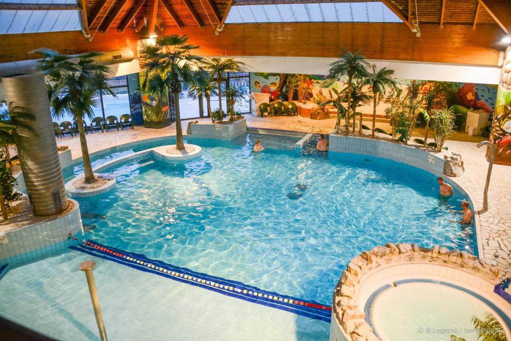 ein großer Pool in einem Hotel mit Palmen in der Unterkunft Résidence Goélia La Pommeraie in Branville