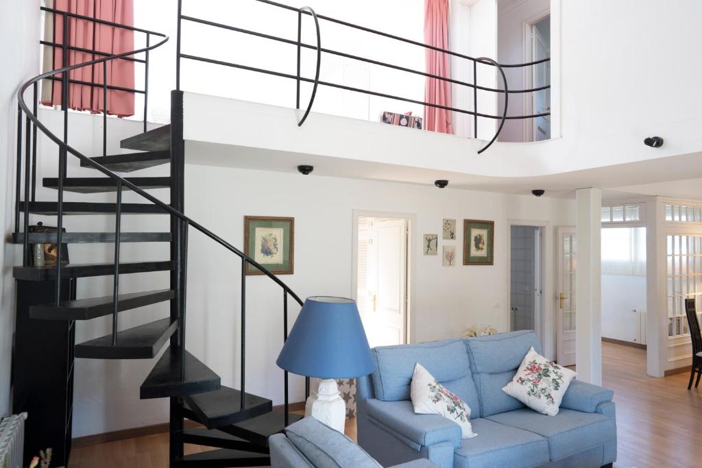 a living room with a blue couch and a spiral staircase at Orquideas in Cala Galdana