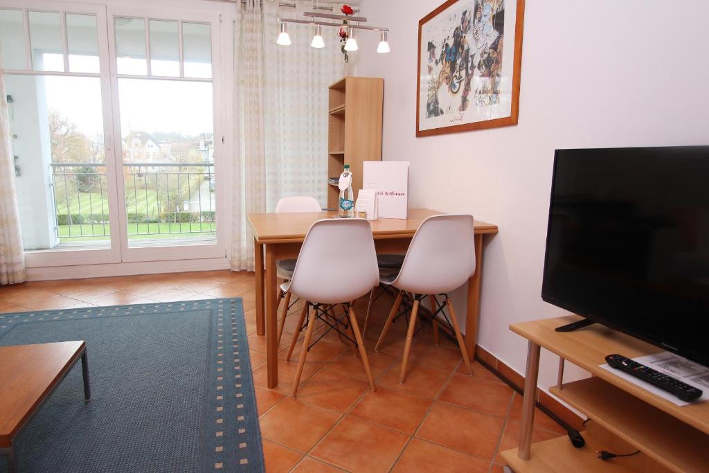 ein Wohnzimmer mit einem Tisch mit Stühlen und einem TV in der Unterkunft Ferienwohnung Sonnenschein - direkte Meerlage in Kühlungsborn