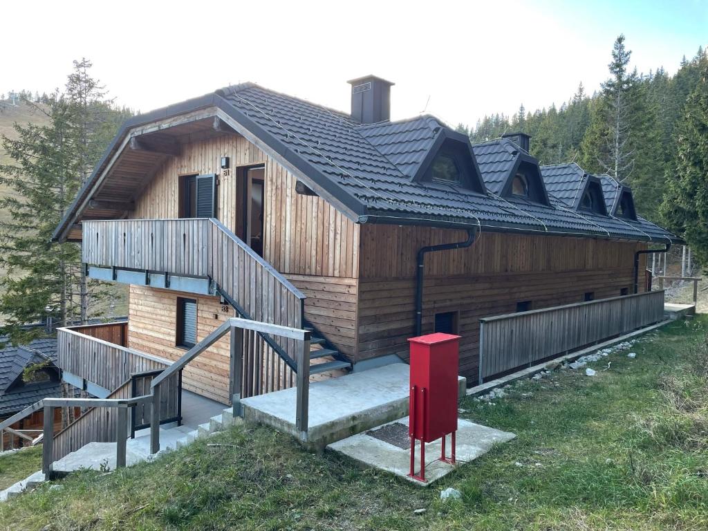a large wooden house with a red object in front of it at Apartma Lilija Golte in Mozirje