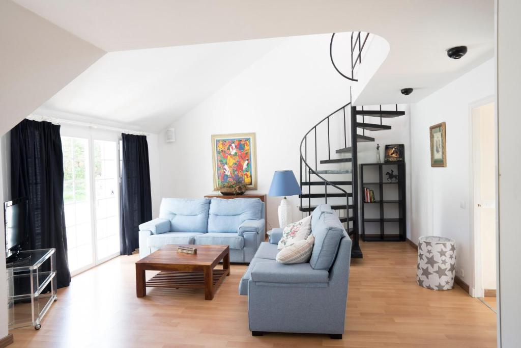 a living room with a blue couch and a spiral staircase at Orquideas in Cala Galdana