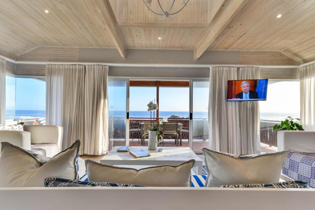 a living room with a view of the ocean at Singing Kettle Beach Lodge in Keurboomstrand