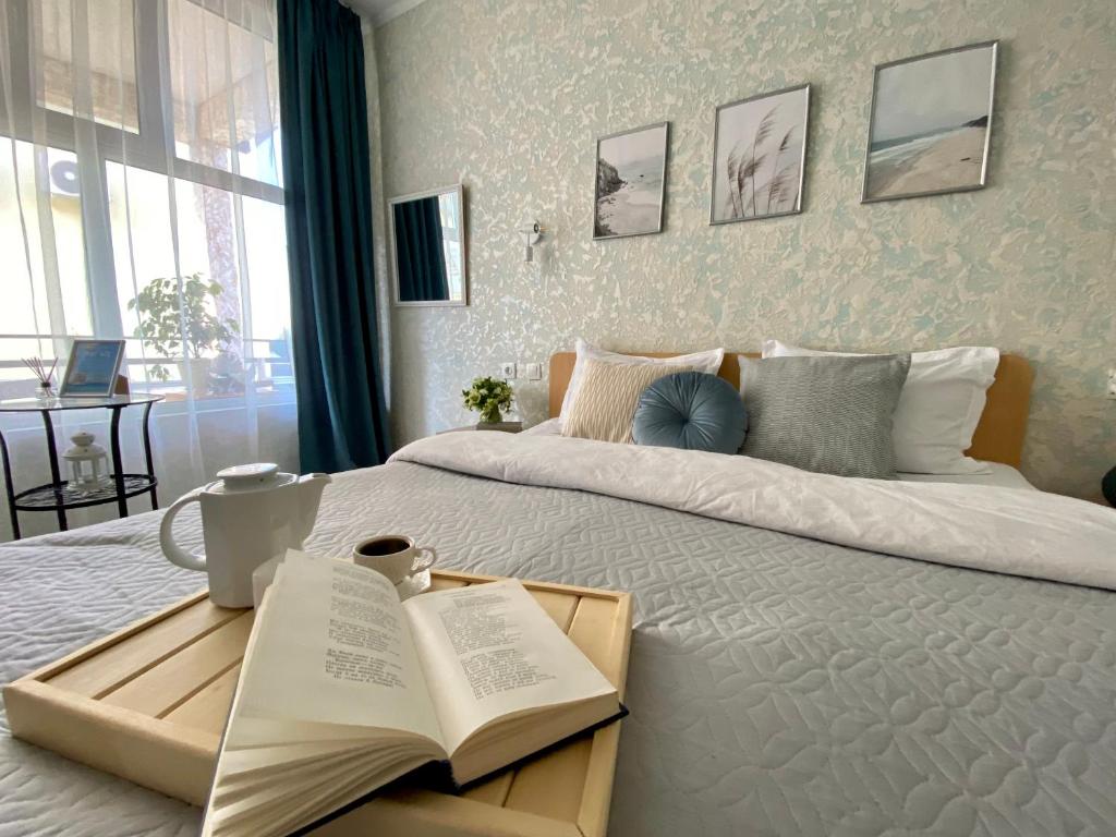 a bedroom with a large bed with a book on it at Мини-отель ДАРЬЯ в Пицунде in Pizunda