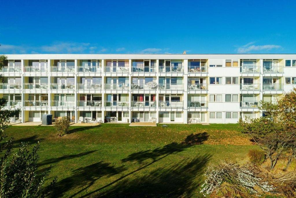 ein großes weißes Gebäude mit einer Wiese davor in der Unterkunft "Strandhotel Heiligenhafen", Wohnung 126 in Heiligenhafen