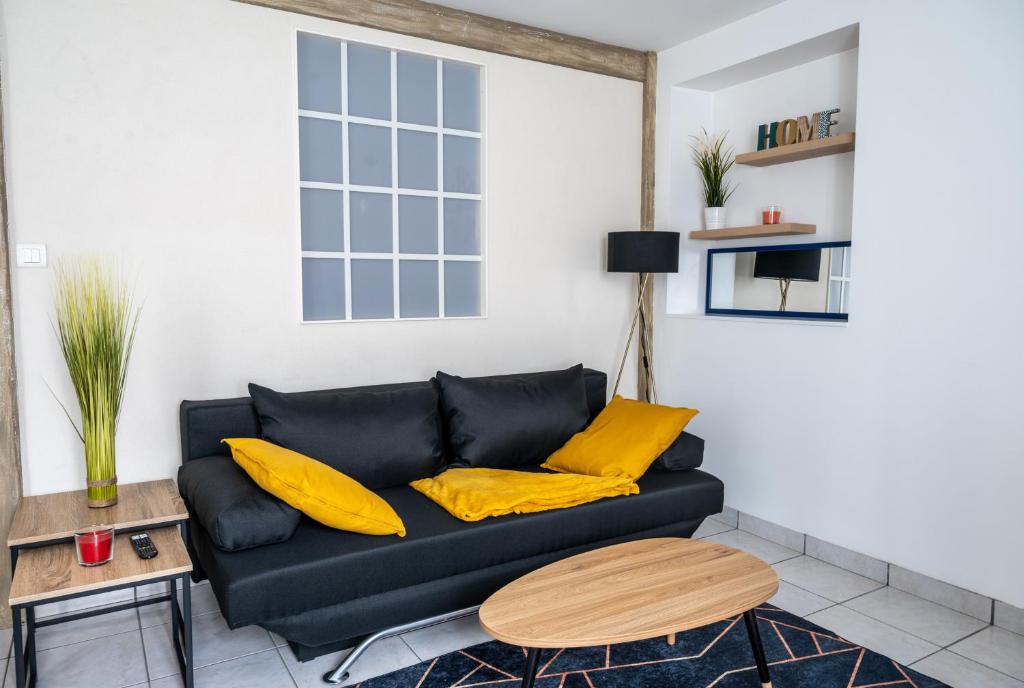 a living room with a black couch and yellow pillows at Le 4midable - Chaleureux 2 pièces in Bouguenais