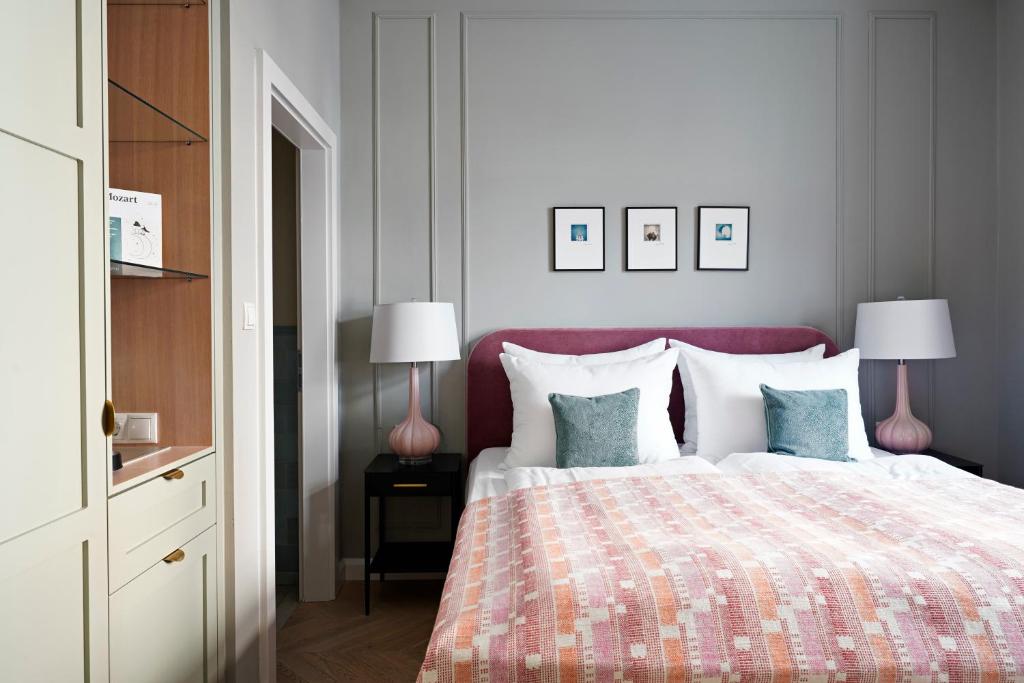 a bedroom with a bed with a pink headboard and two lamps at numa l Mozart in Salzburg