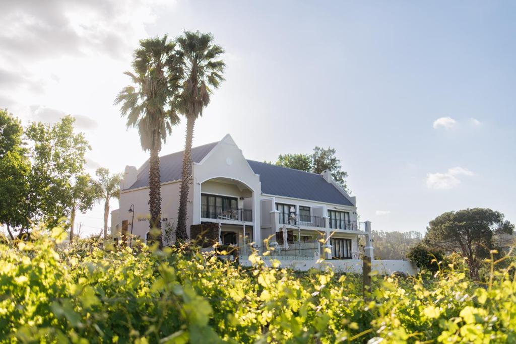 una casa blanca con palmeras en el primer plano en Banhoek Lodge, en Stellenbosch