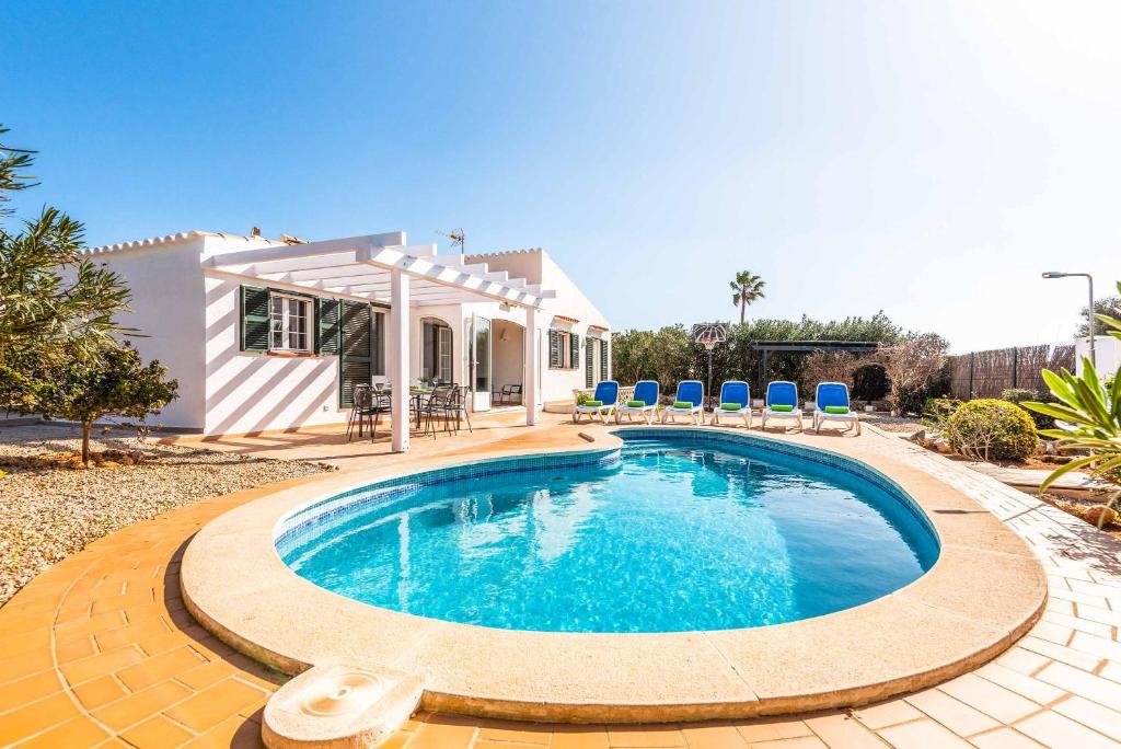 a swimming pool in front of a house at Villa Mimosa in Binibeca