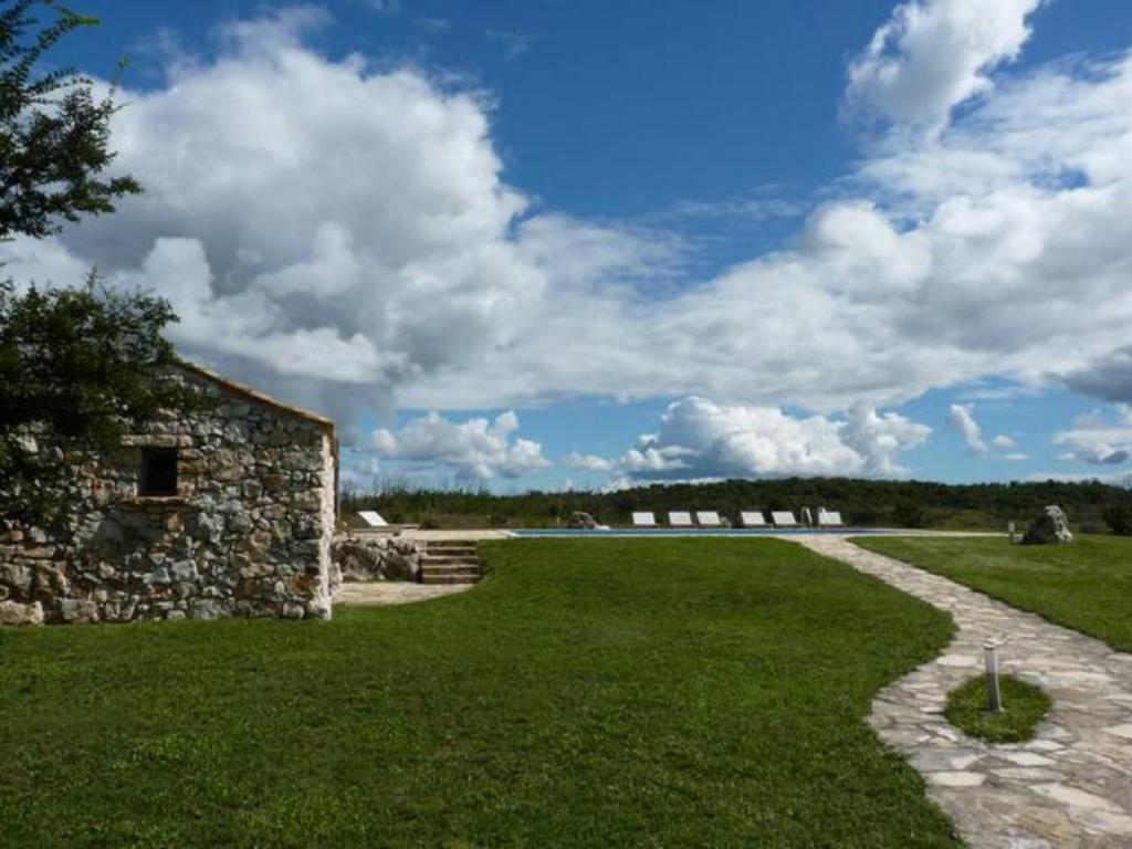 un bâtiment en pierre et une pelouse avec un sentier dans l'établissement At Home In Istria- Villa Stancia Cicada, à Žminj