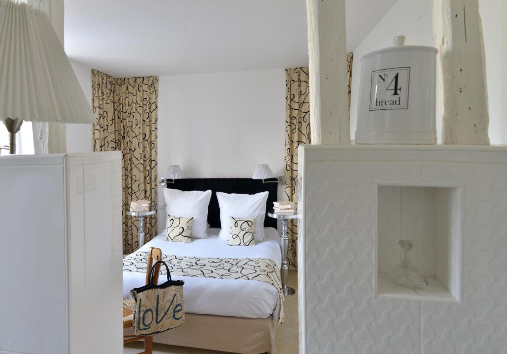 a white bedroom with a bed and a fireplace at Logis Hôtels Restaurant Les 3 Rois in Issoudun