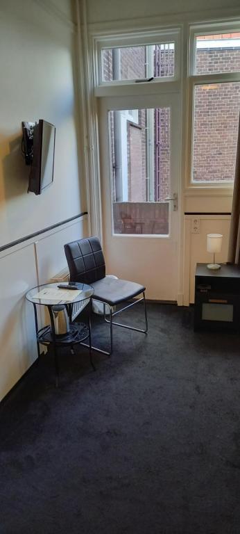 a room with a chair and a table and a window at Stad &amp; Strandhotel Elisabeth in Vlissingen
