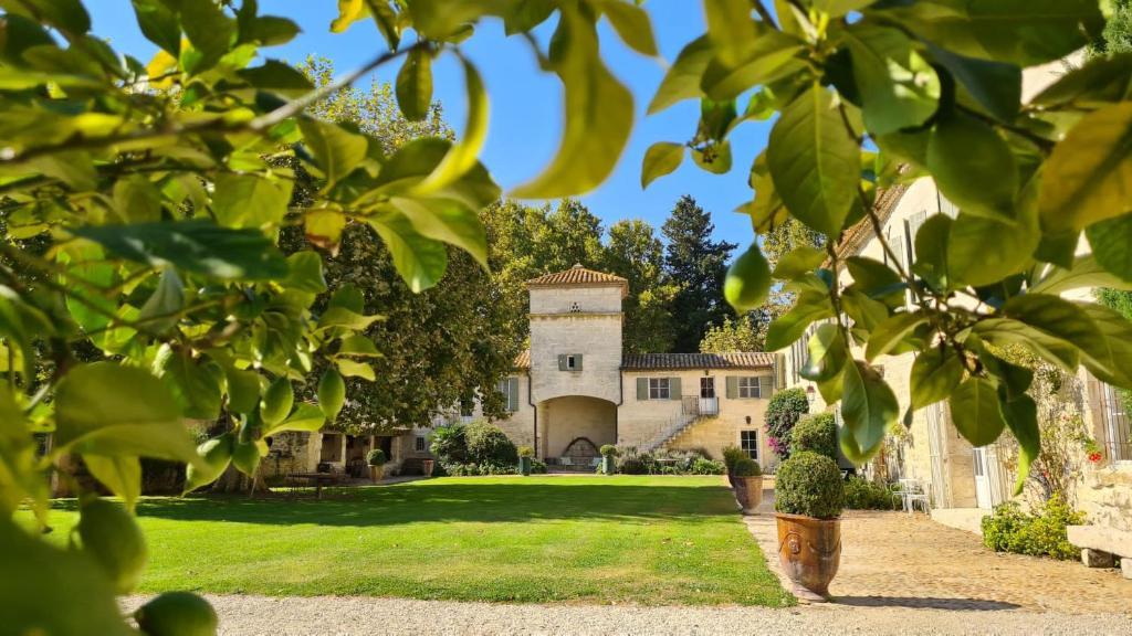 una casa grande con un patio verde con árboles en HOTEL et APPARTEMENTS DOMAINE DES CLOS - Teritoria, en Beaucaire