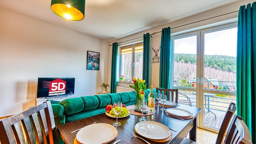 a dining room with a green couch and a table at Apartament Cichy - 5D Apartamenty in Świeradów-Zdrój