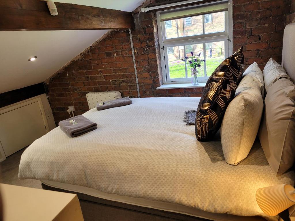 Cama grande en habitación con pared de ladrillo en Carlisle Central, Cute Studio Appt, The Cupboard en Carlisle