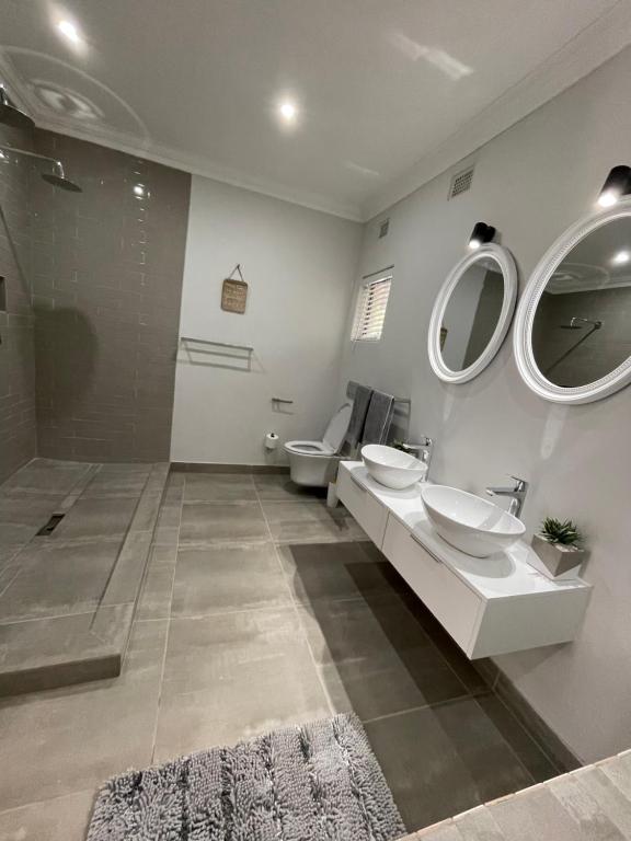 a bathroom with two sinks and a shower and mirrors at Guest house on Gillian Unit 6 in Ballito