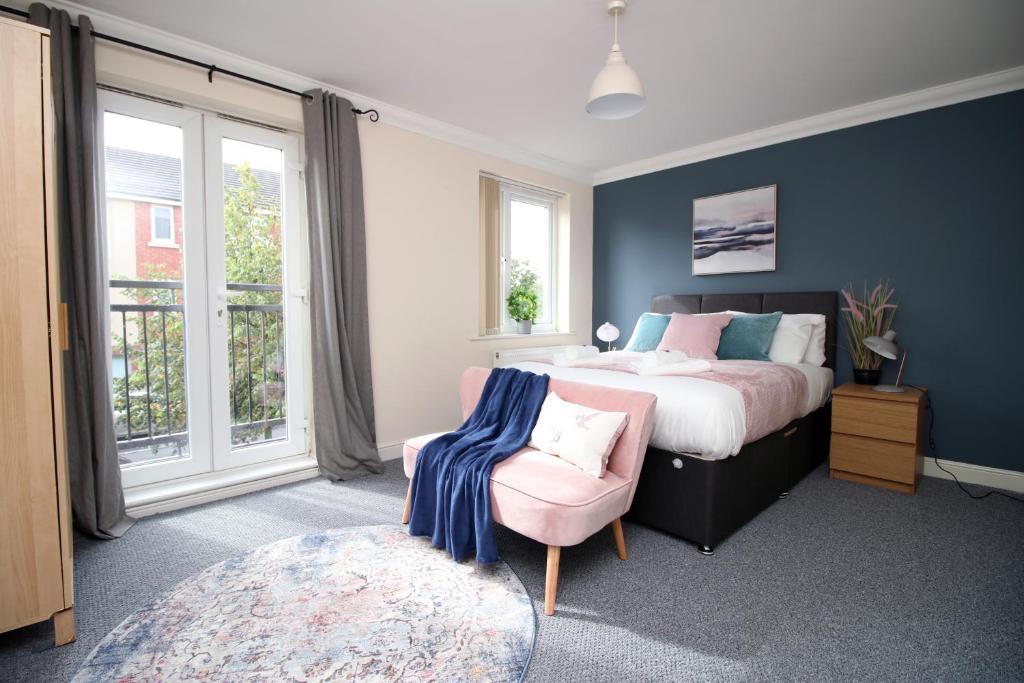 a bedroom with a bed and a chair and windows at Alicia's Way by Tŷ SA in Newport