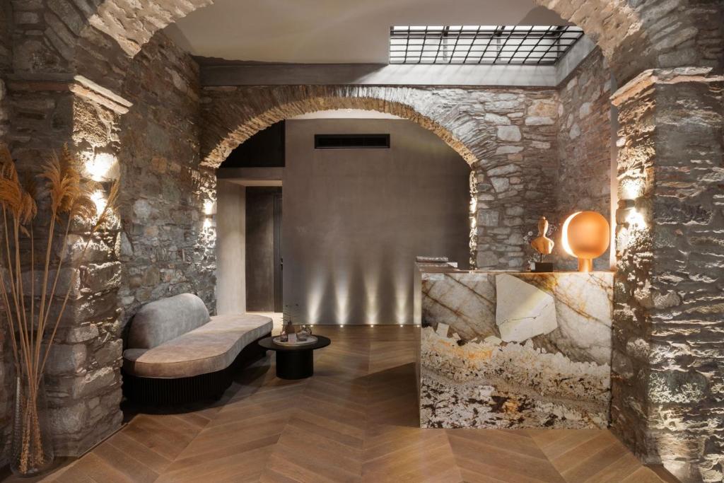 a lobby with a stone wall with a bench and a table at Castro Hotel Syros in Ermoupoli