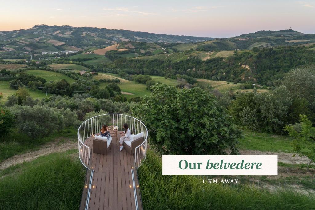 un grupo de personas sentadas en una terraza con vistas a las colinas en Relais Cocci Grifoni - Panoramic Wine Resort, en Offida