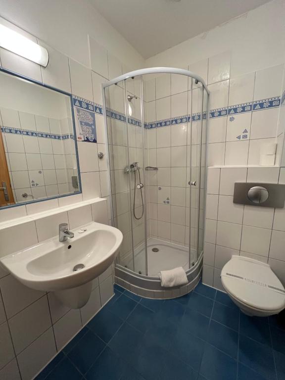 a bathroom with a shower and a sink and a toilet at Hotel Boston in Karlovy Vary