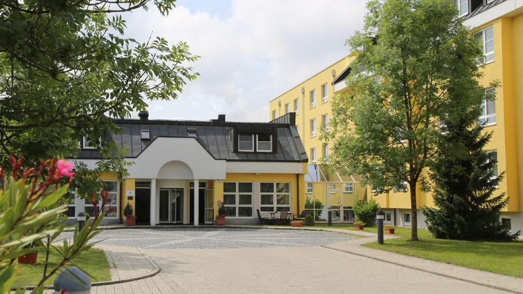 Blick auf ein gelbes Gebäude in der Unterkunft Hotel Alarun in Unterschleißheim
