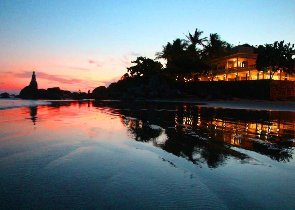 a sunset on a beach with a house in the background at Pousada Sobre as Pedras in Itanhaém