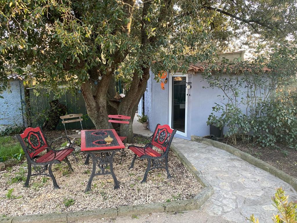 une table et quatre chaises assises sous un arbre dans l'établissement STUDIO Havre de paix au pont du gard Piscine et Jacuzzi chez Valerie Payre, à Vers-Pont-du-Gard