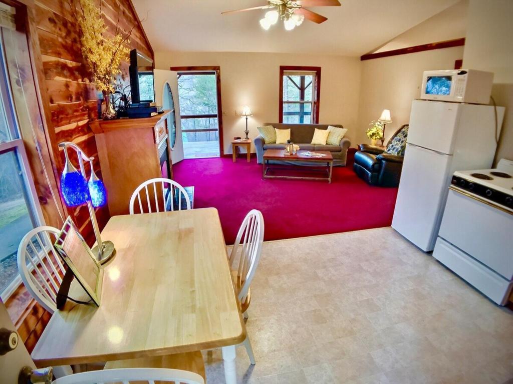 uma cozinha e sala de estar com uma mesa e um frigorífico em Cedar Creek Cabins em Eureka Springs