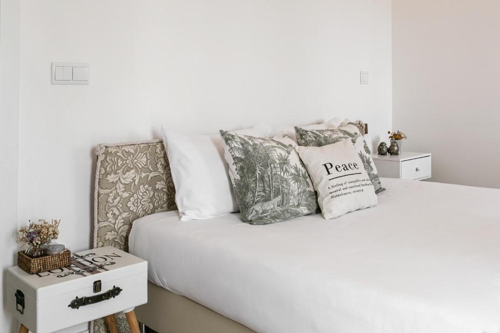 a bedroom with a white bed with pillows on it at Casa Trilhos da Serra in Alcobertas