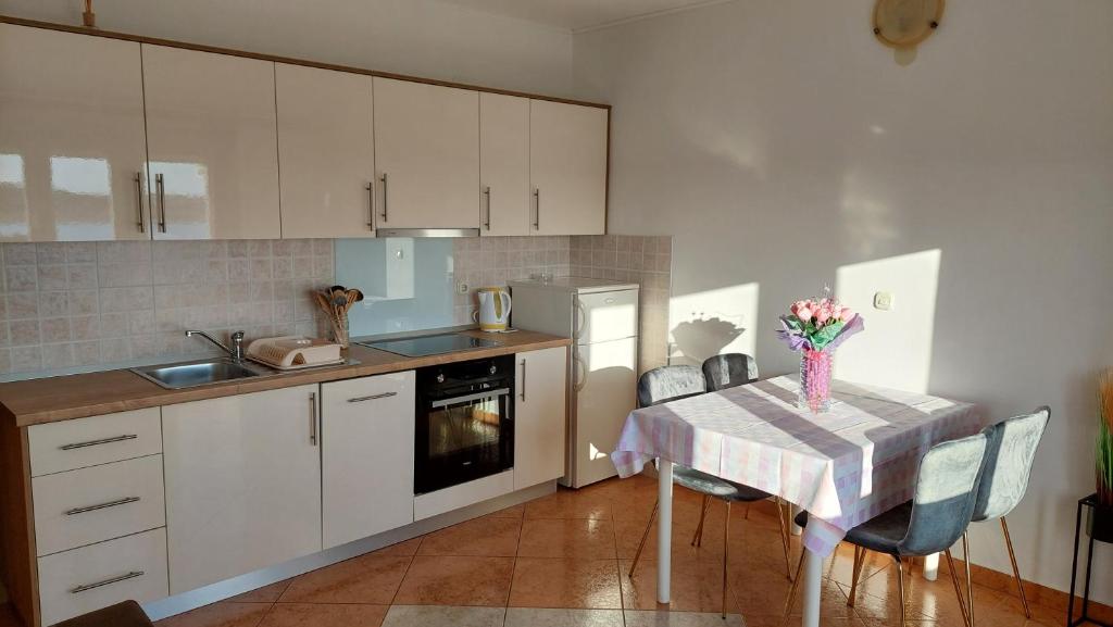 a kitchen with a table with a vase of flowers on it at Apartments Donadic I, Caska in Novalja