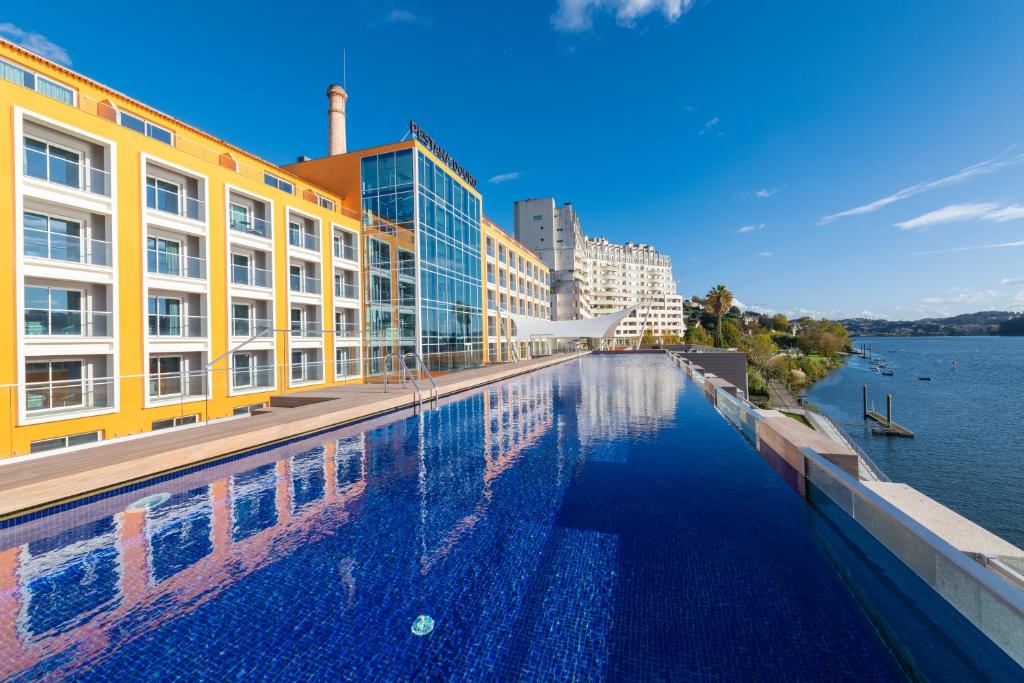 a swimming pool in front of a building next to the water at Pestana Douro Riverside - Preferred Hotels & Resorts, Lifestyle in Porto