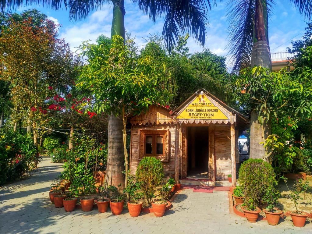 a small building with trees and plants in pots at Eden jungle resort in Sauraha