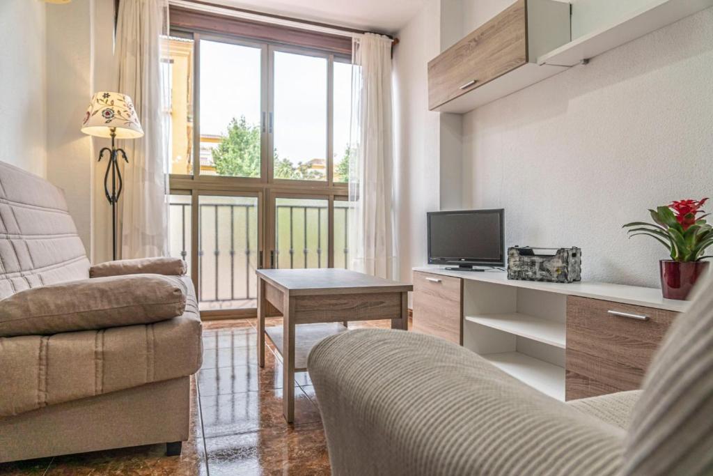 ein Wohnzimmer mit einem Sofa und einem Schreibtisch mit einem TV in der Unterkunft Apartamento Señorio in Rincón de la Victoria