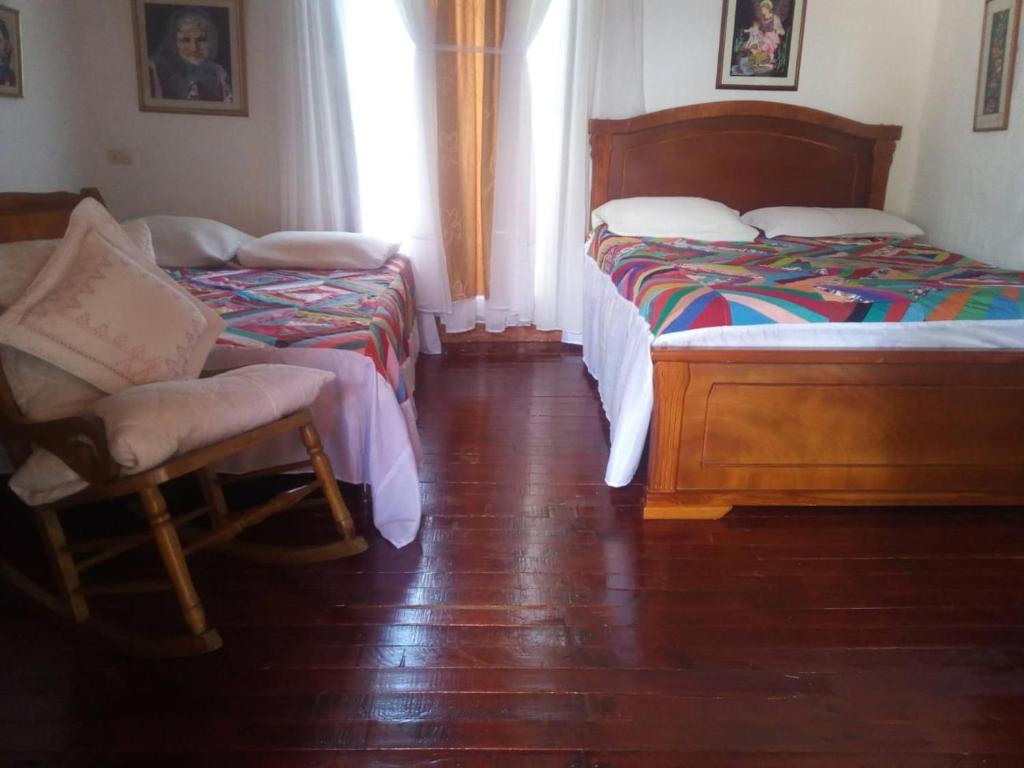 a bedroom with two beds and a chair in it at Casa Patrimonial Abejorral - CASA GASAMA in Abejorral