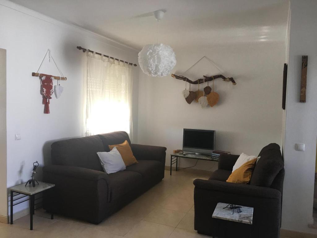 a living room with a couch and a tv at Casa Quintião in Ferragudo