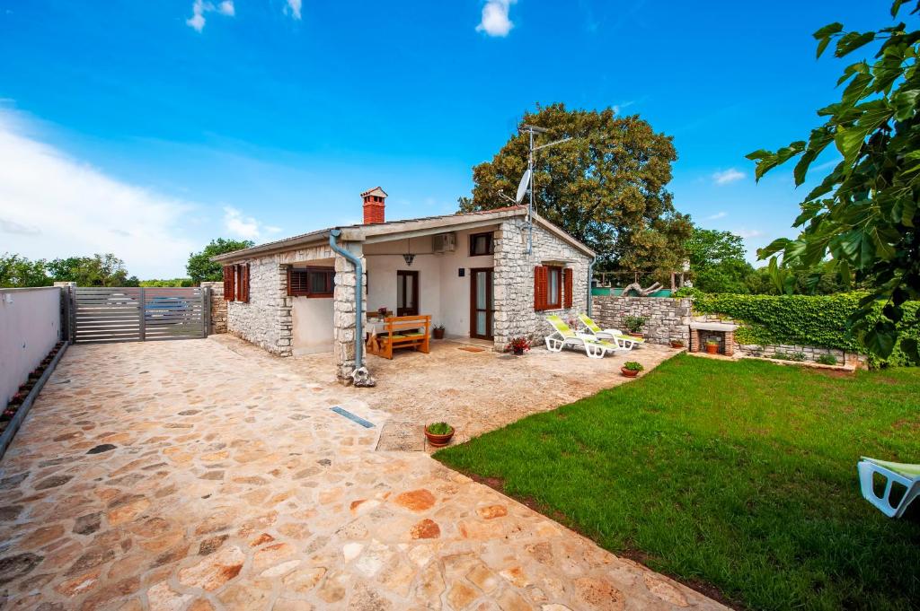 a small stone cottage with a patio and grass at Charming House Nino with a fenced yard in Krmed